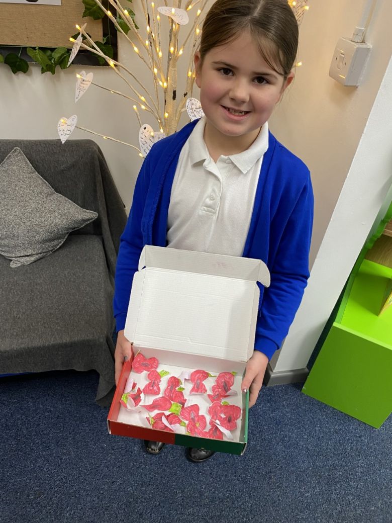 Child holding box of paper poppies.